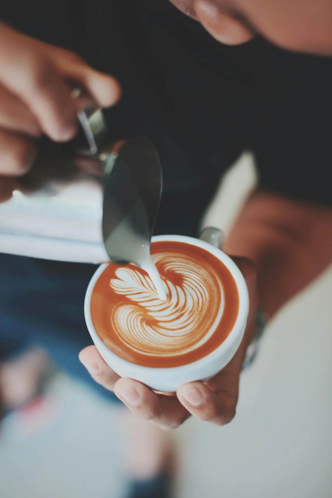 Pouring milk foam onto espresso to create a cappuccino